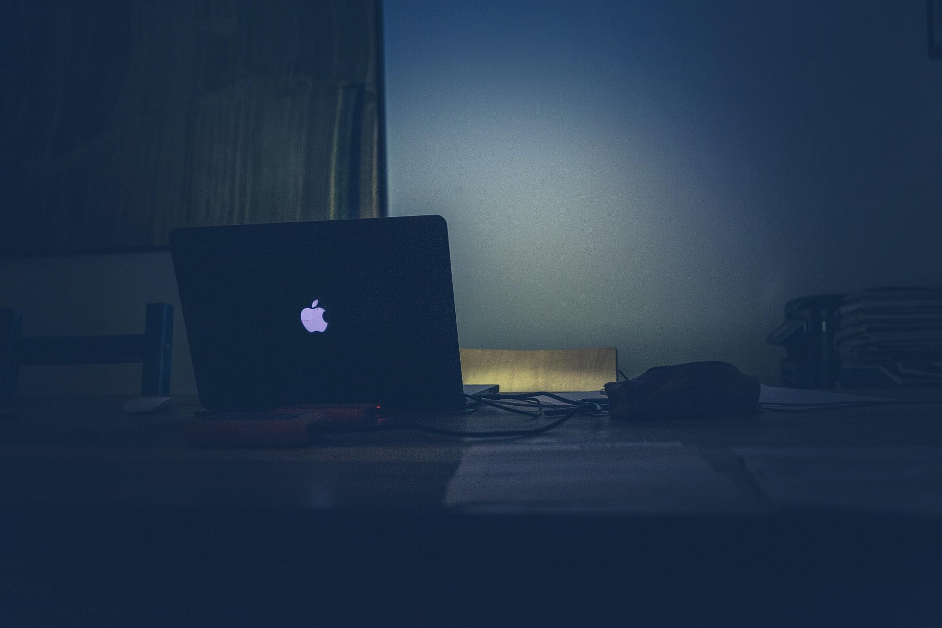 Laptop glowing in a dark office at night, symbolizing AI’s growing authority and the loneliness of modern programming work